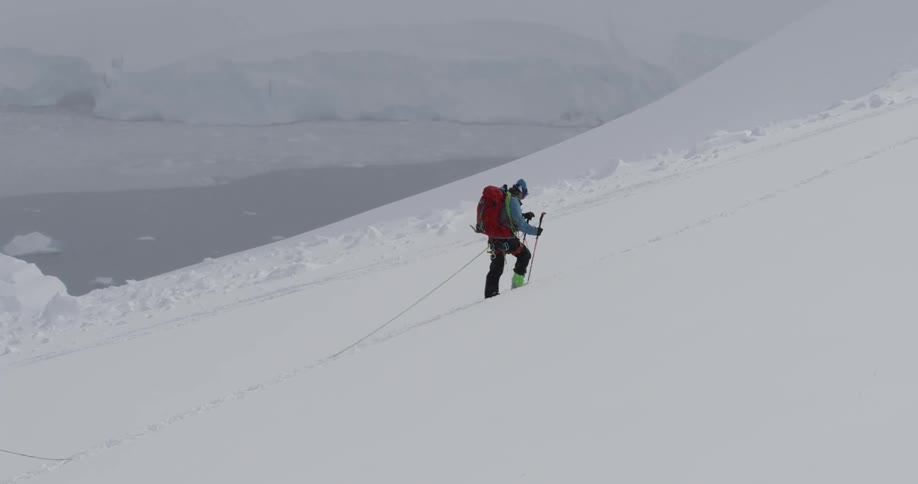 A skier hikes up a snowy mountainside