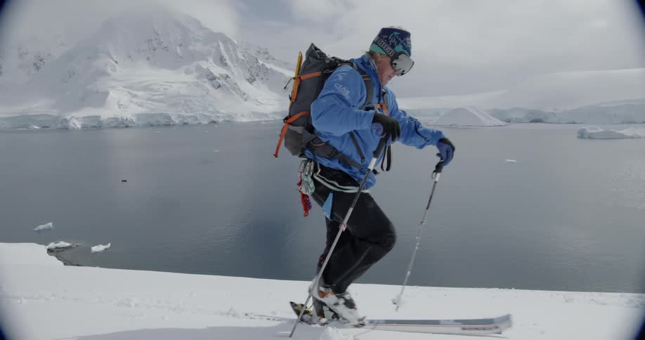 A man moves along the snow in skis by the water