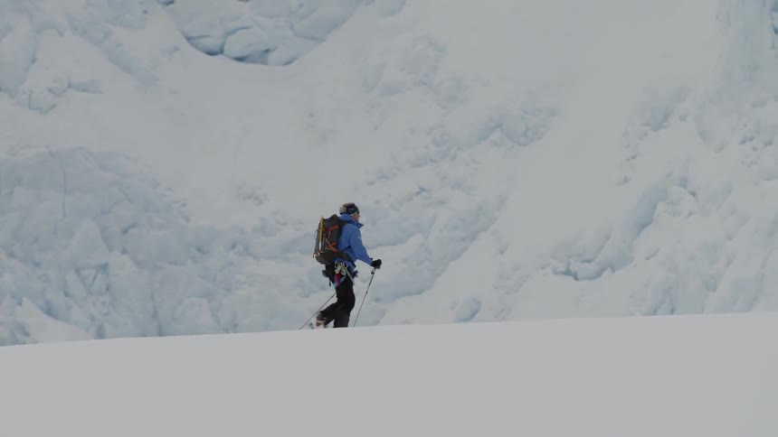 Person wearing skis walks on snowy terrain using ski poles