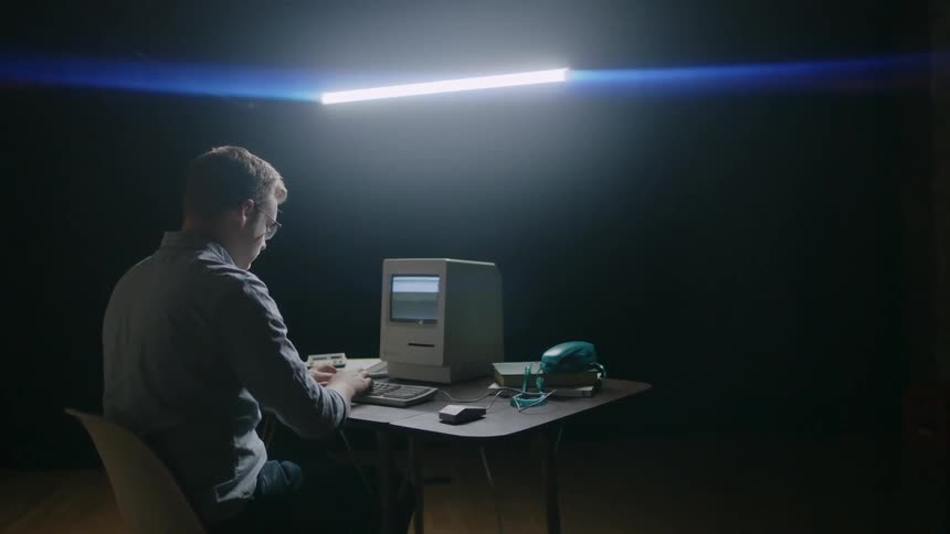 A man sits at a table and works on a computer