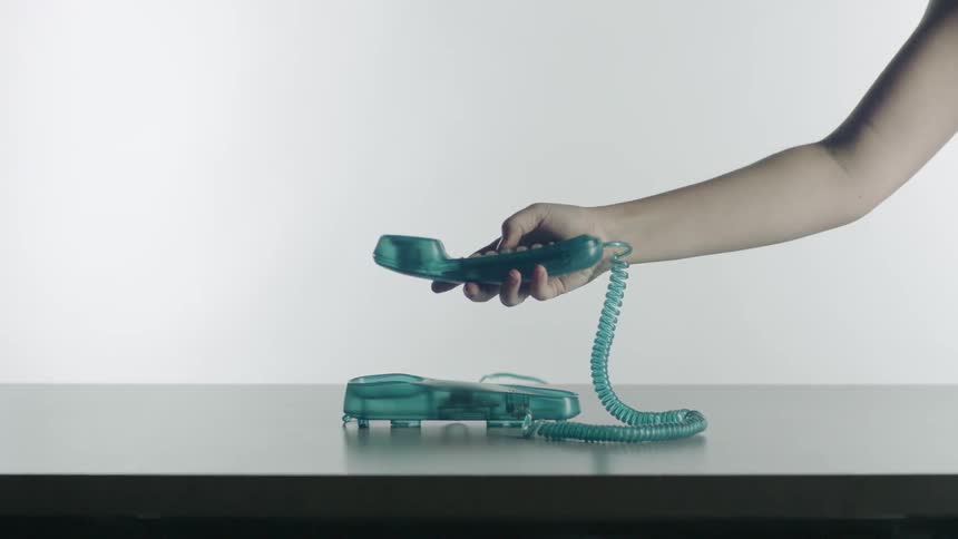 Person's hand picks up and dials on an old fashioned landline phone