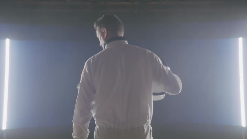A man wearing an astronaut suit is standing in a room holding a helmet