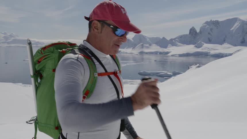 A skier hikes up a snowy mountainside