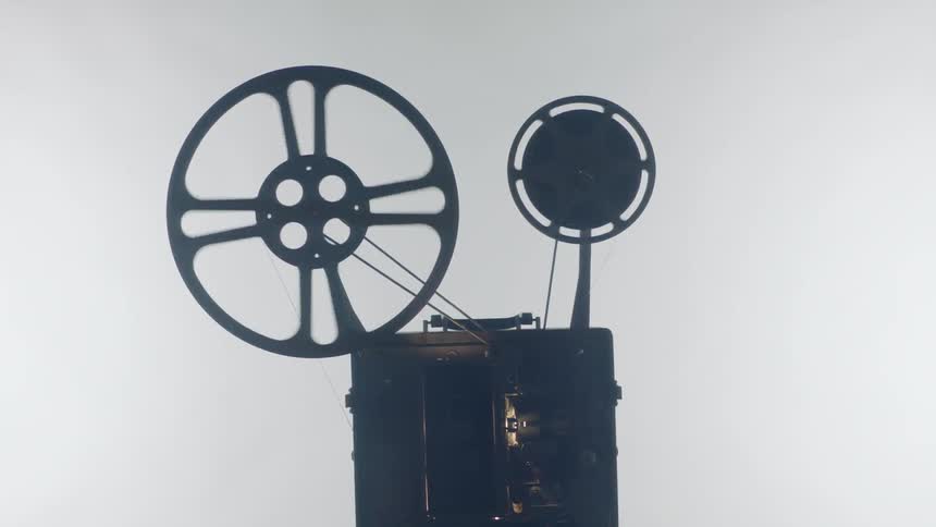 Projector spinning its reels of film against a light background