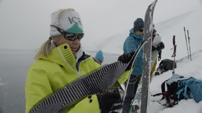 Woman applies grip tape to the bottom of her skis