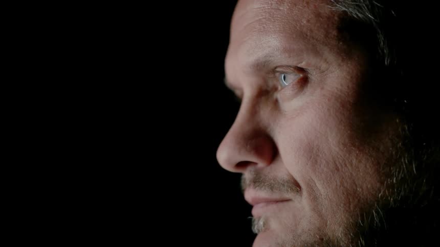 A man sitting in thought begins to look up into the light