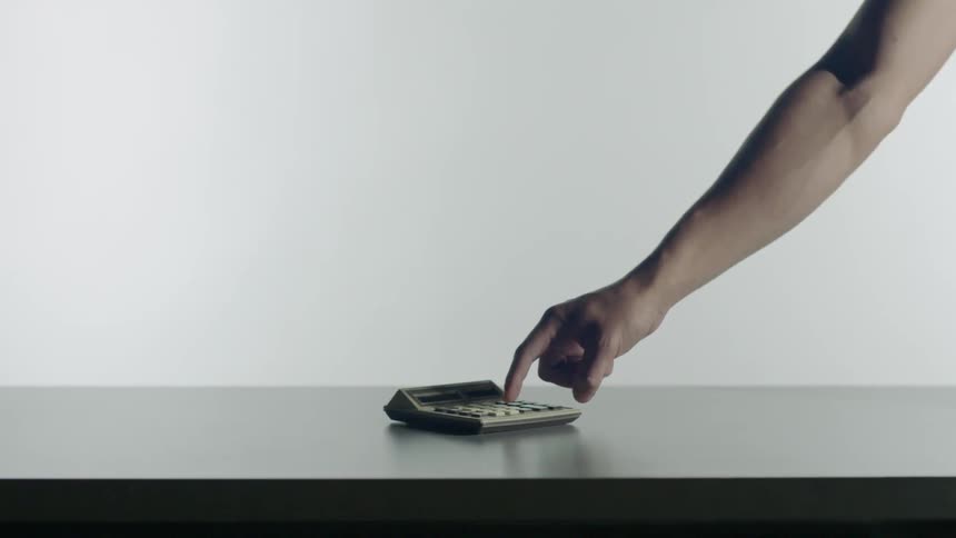 Man presses keys on a desktop calculator