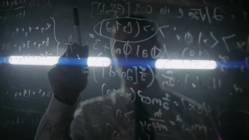A man does math equations on a dry erase board