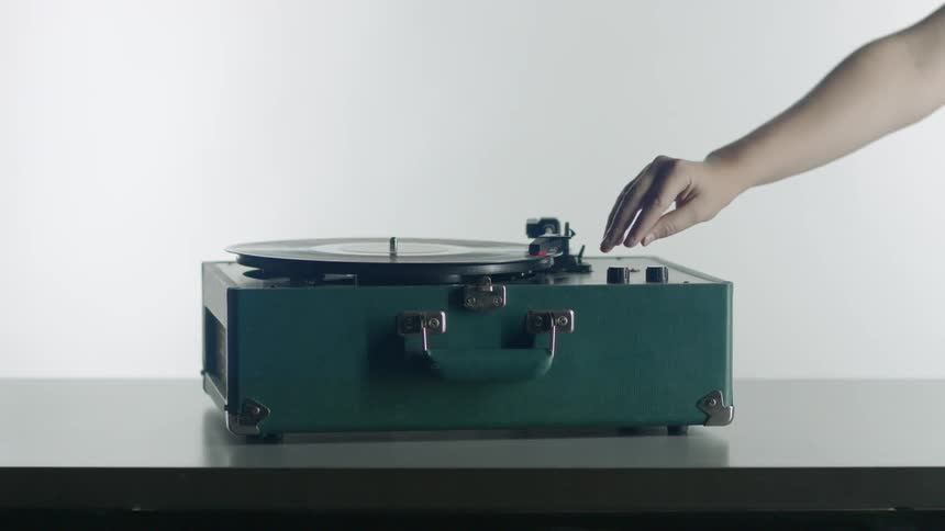 Woman moves record player arm over onto the record