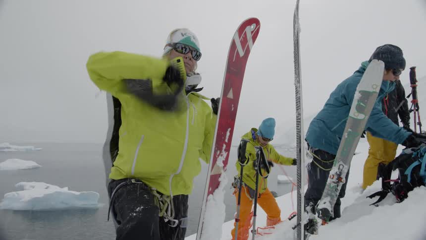 Three people prepare to walk up a snowy mountain