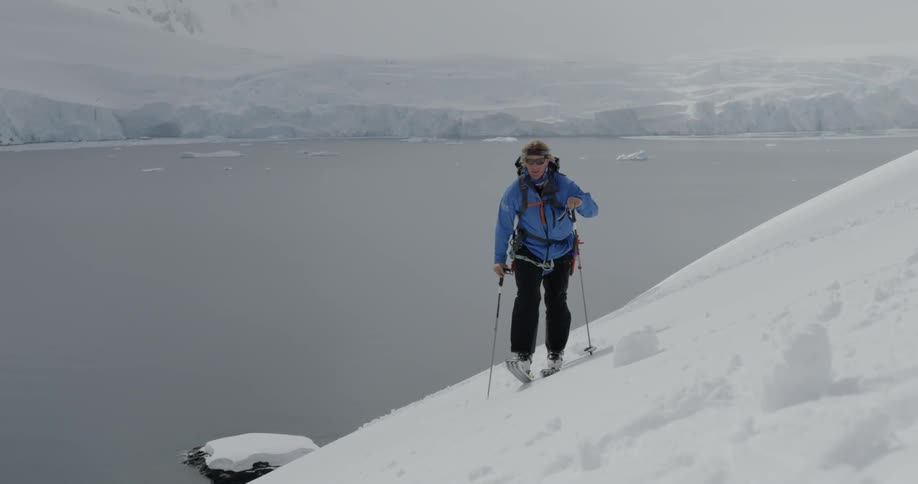 The person is hiking through the snow on the side of the hill