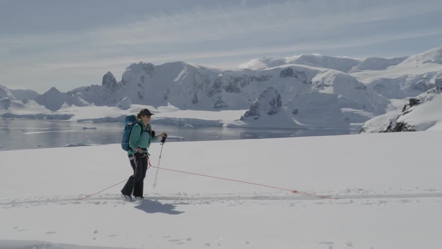 A woman is snowshoeing across a frozen landscape in daylight
