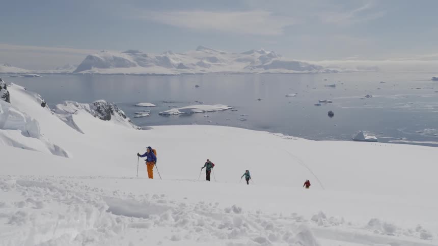The people are hiking up the slope near the shore