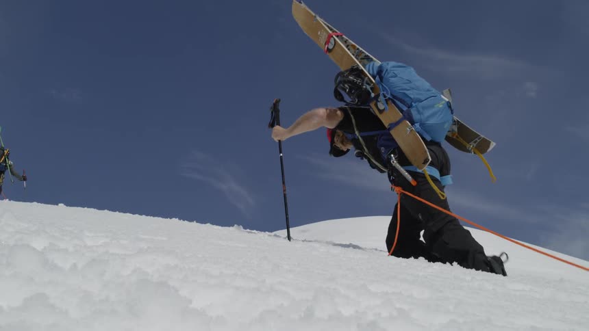 A skier hikes up a snowy mountainside