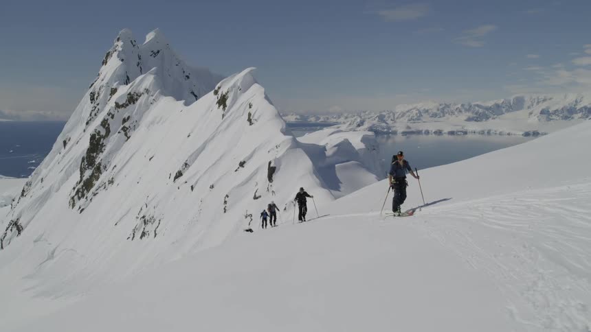 Skiers hike up a snowy mountainside