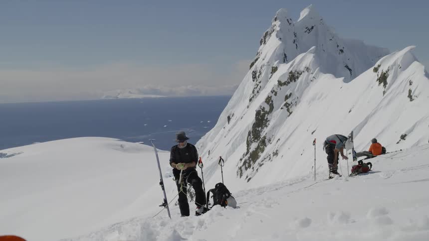 Skiers stand on a snowy mountainside