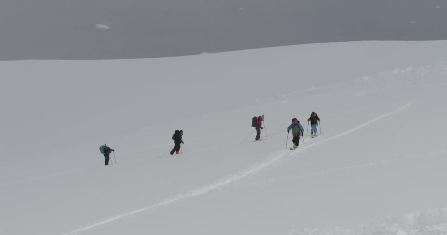 Skiers hike up a snowy mountainside