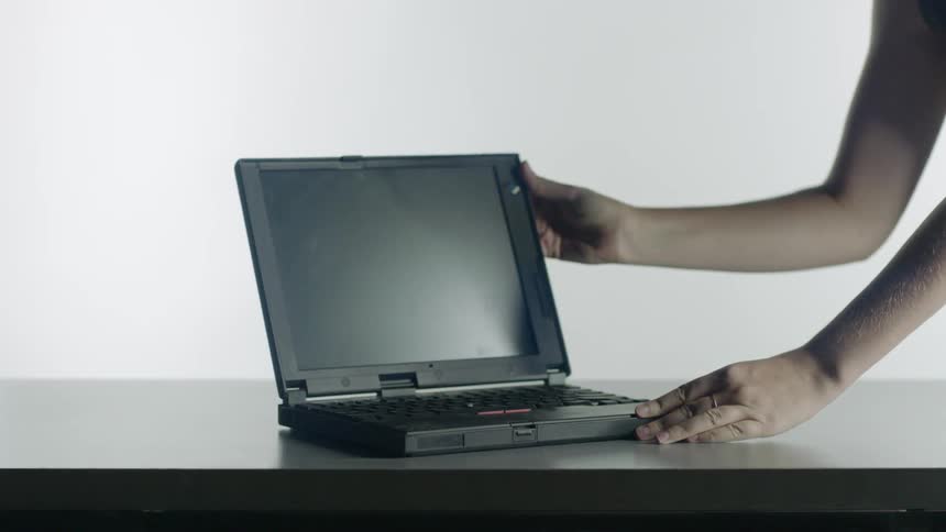 A person's hands open up a laptop on a table