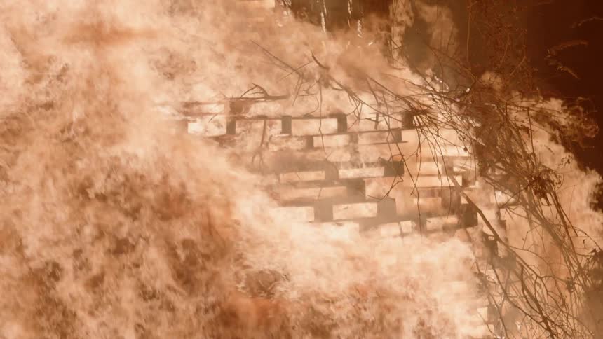 Fire blazes brightly and burns through a wooden structure