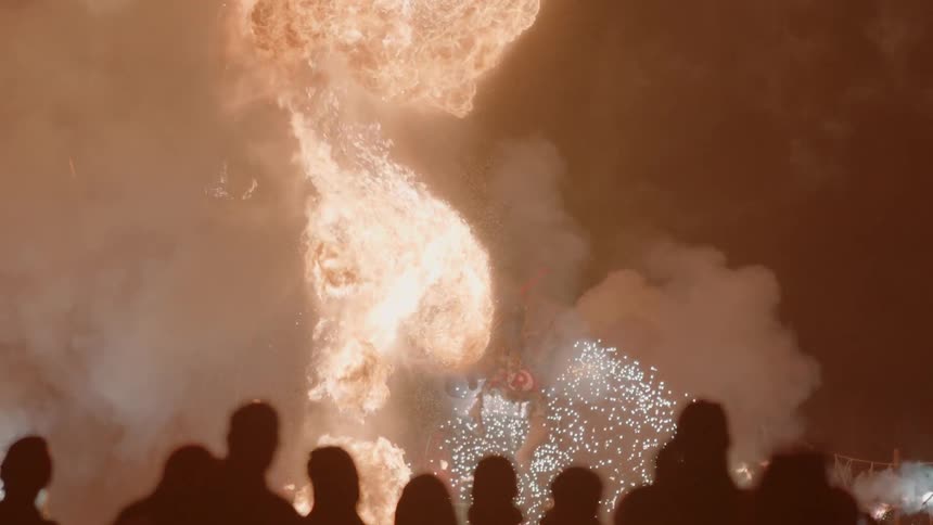 People watch as flames burst during a fireworks show