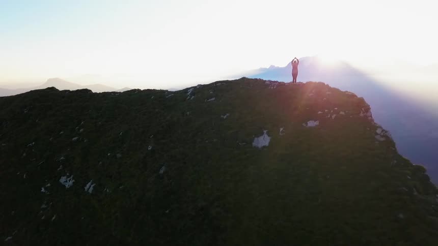 A person stretches on a mountain at sunrise