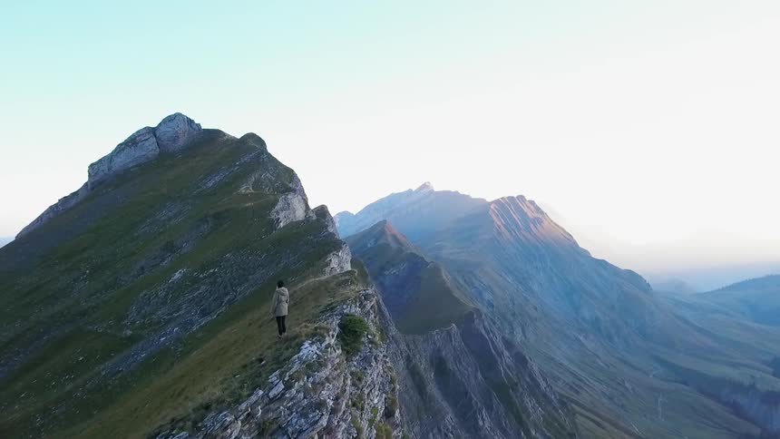 A person stands on a rocky ridge