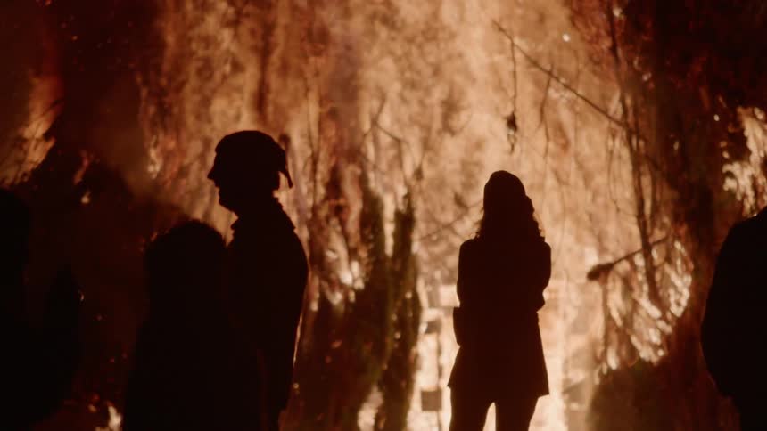 People are standing near a bonfire burning at night