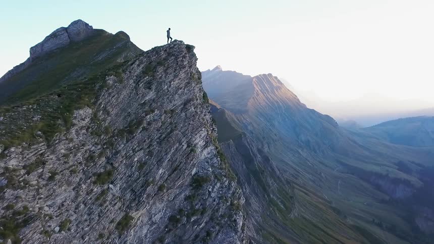 A person is standing on a mountain ridge taking in the view
