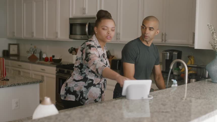 A woman walks over to the sink to show something to a man