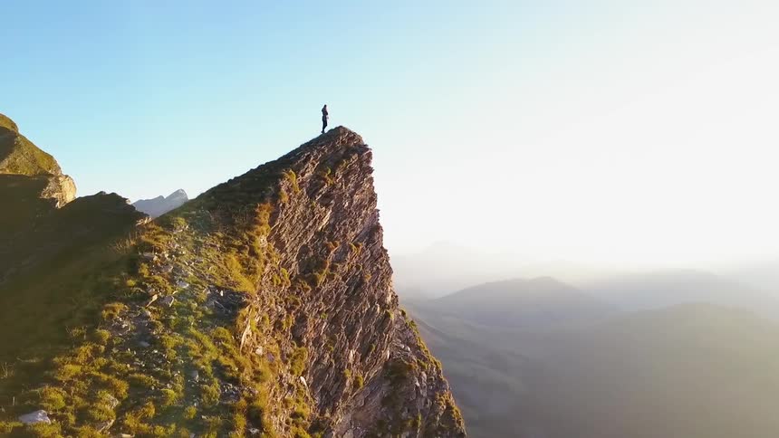 Person stands on the peak of a mountain