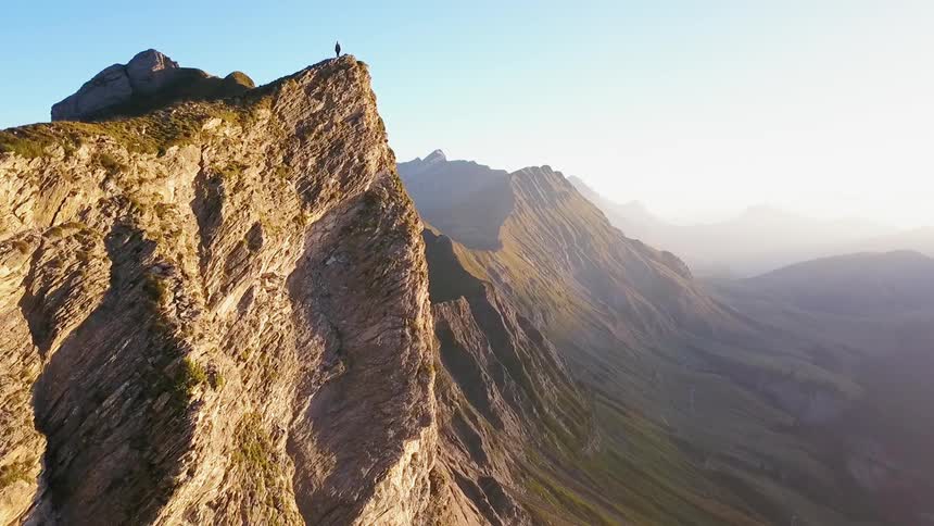 A hiker stands on a mountain peak