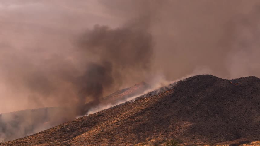 A fire burns on the side of a hill