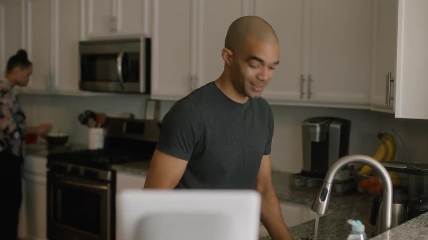A couple clean and cook as they talk in the kitchen