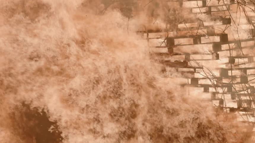 Fire blazes brightly and burns through a wooden structure