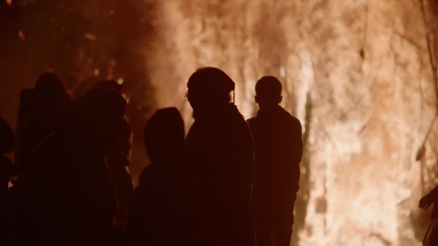 The people walk past the huge bonfire