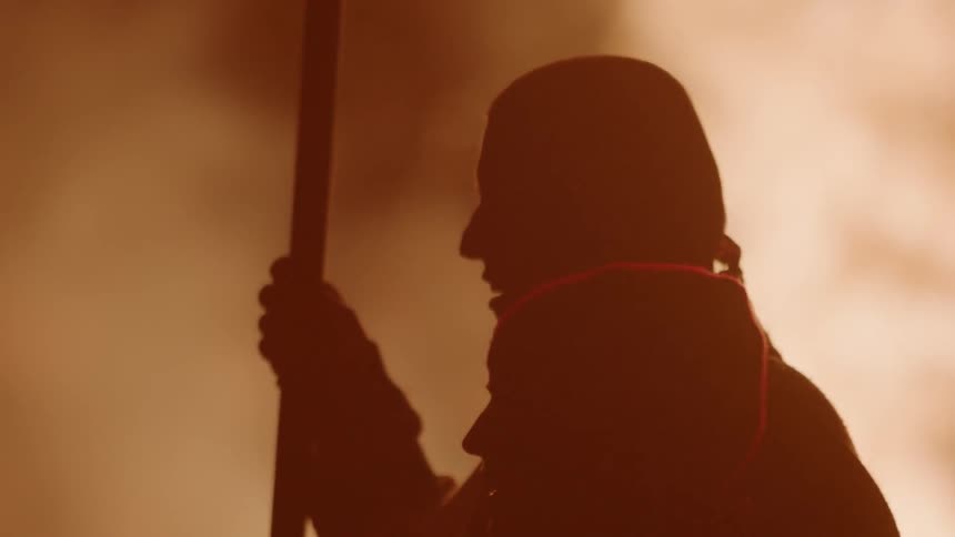 A man is holding a stick by a large fire