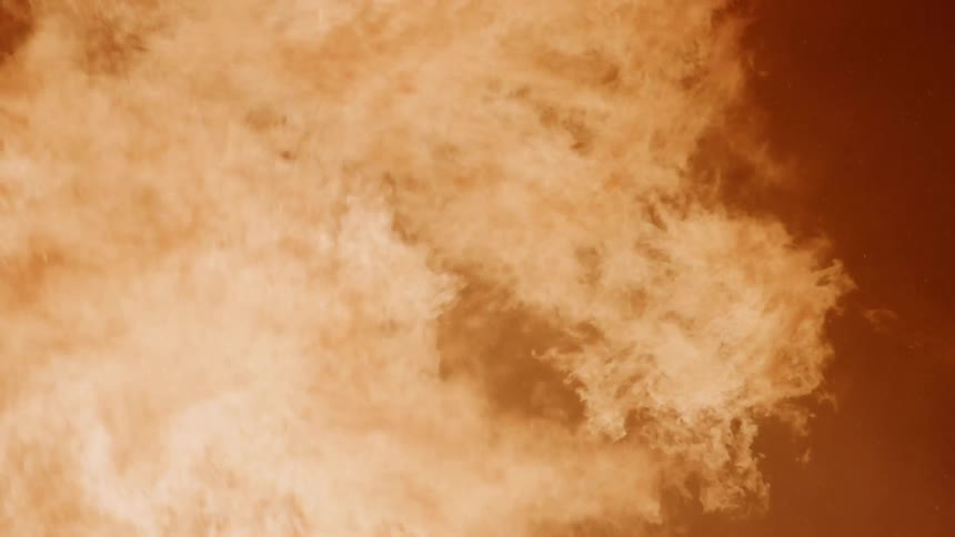 A large fire burns outside at night