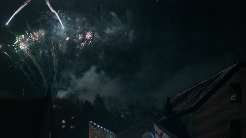 Fireworks explode in the sky high above the city