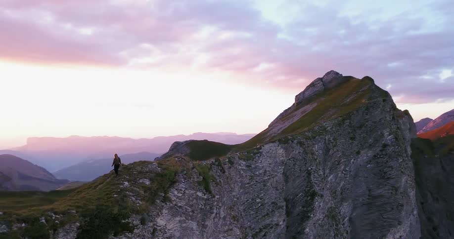 A person is hiking over the tall green mountain