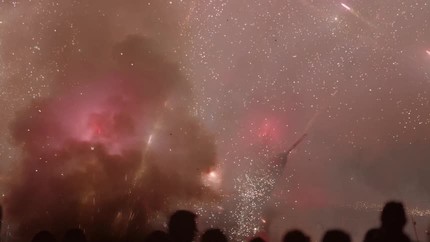 A crowd is watching fireworks explode around them at night