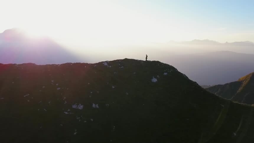 A man walks atop a tall mountain