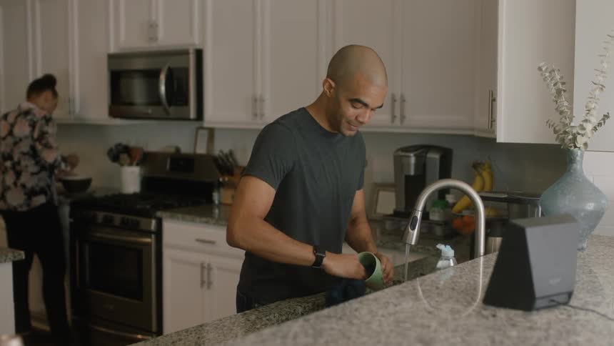 A man and woman wash dishes and cook in a kitchen