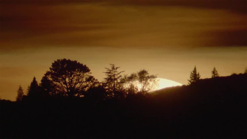 The sun completely sets behind the hills ahead