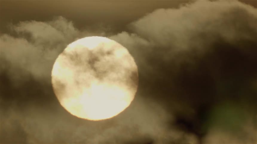 Clouds pass in front of the large sun