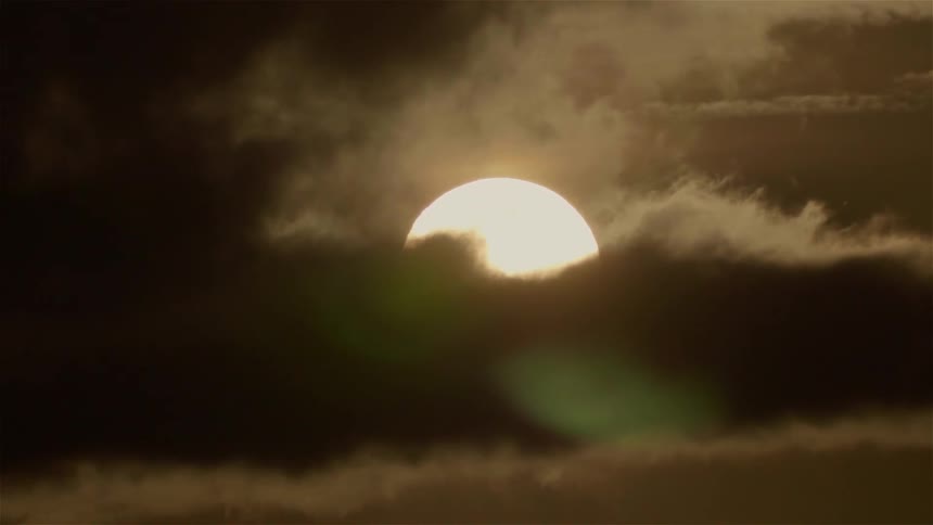 Clouds pass in front of the large sun
