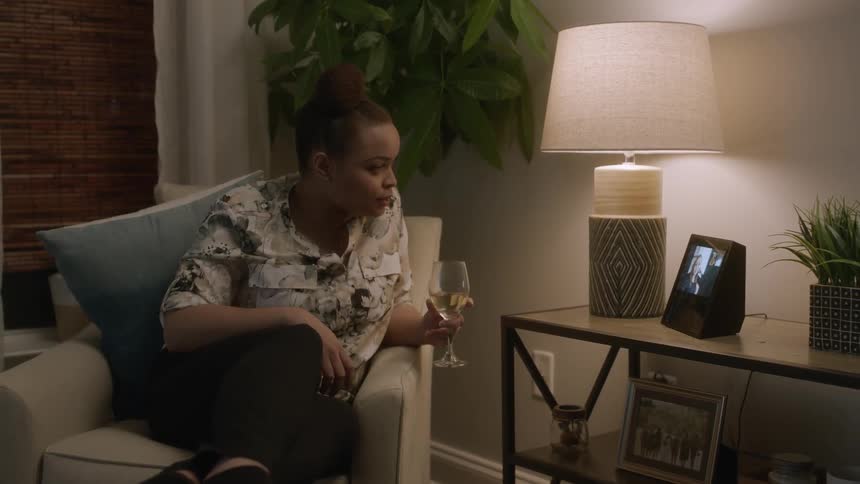 Woman sits in a chair holding a glass of wine leaning over and talking