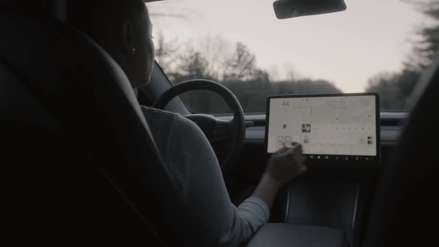 A woman is using a navigation system as she drives a vehicle in daylight