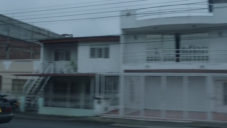 People ride their vehicles down the street on a cloudy day
