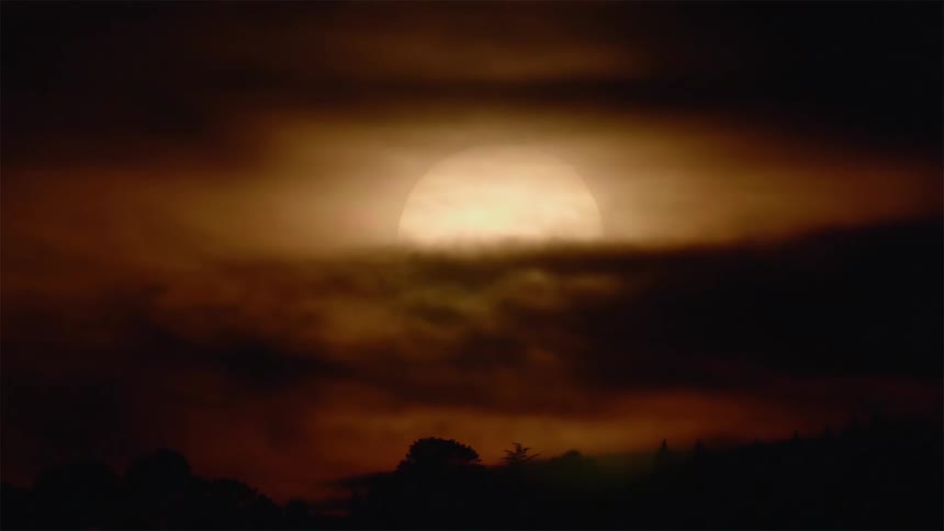 Sun partially covered by clouds sinks slowly