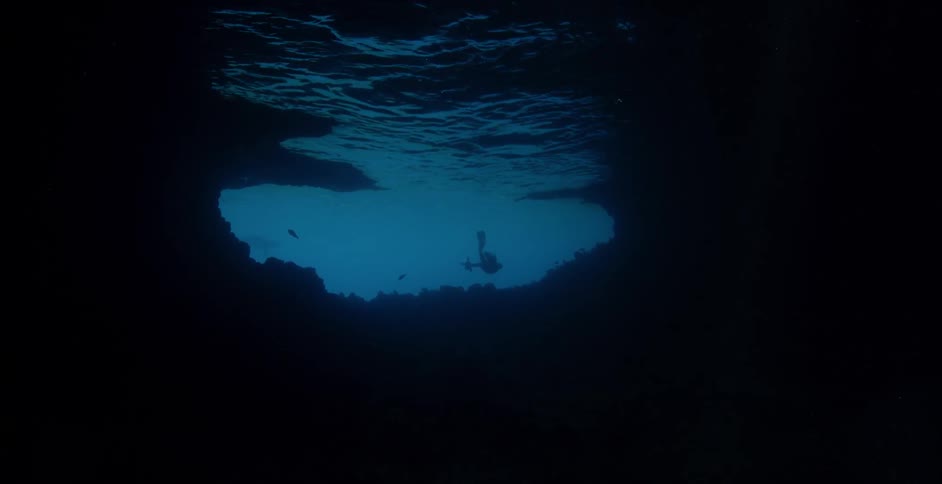 A diver swims underwater in the dark